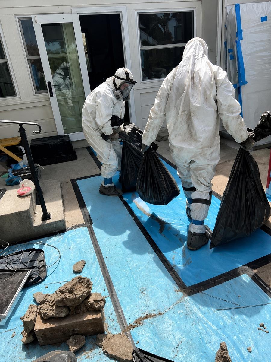 Remediation crew carrying debris to the doorway