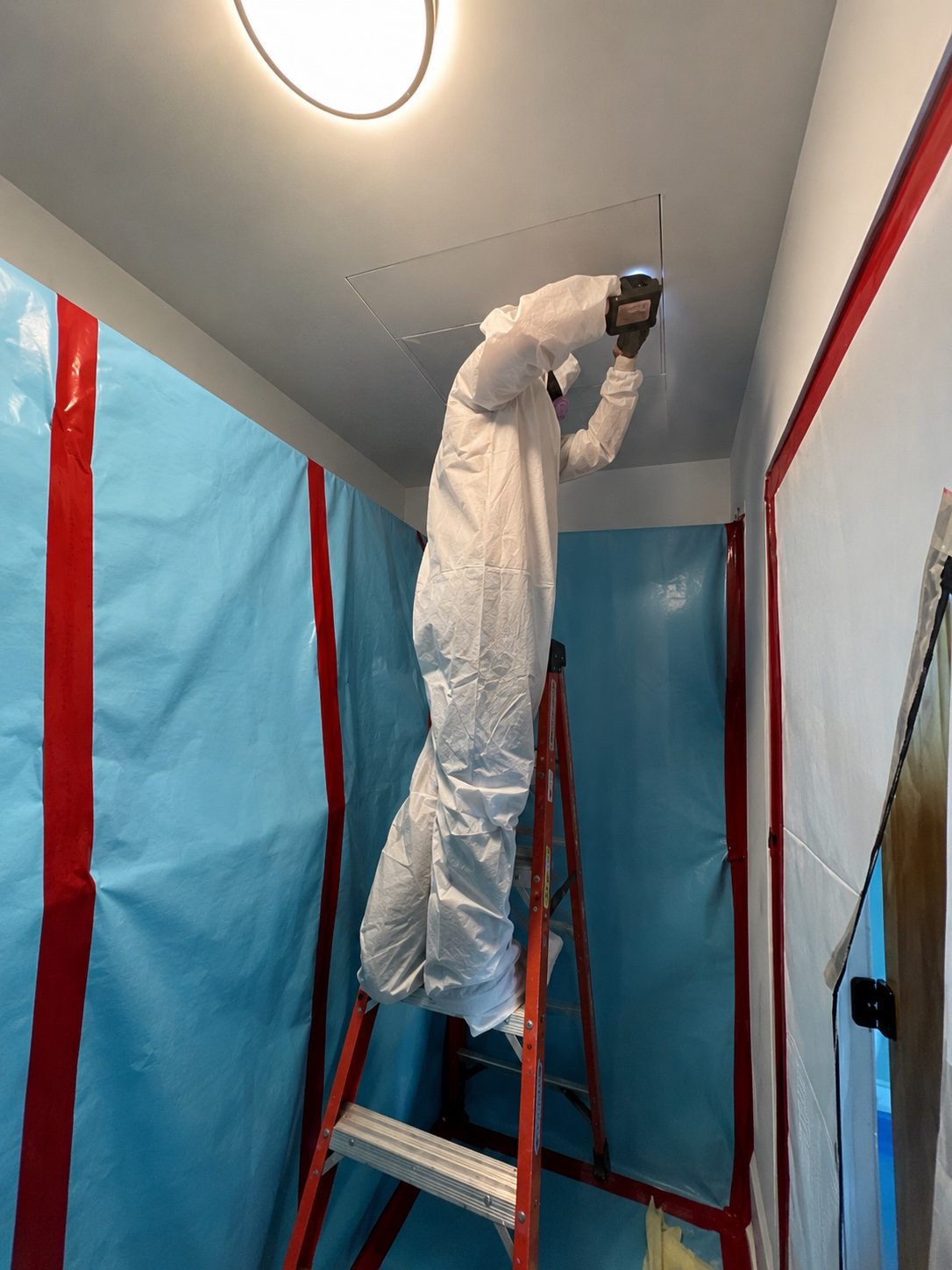 Technician preparing a ceiling during containment